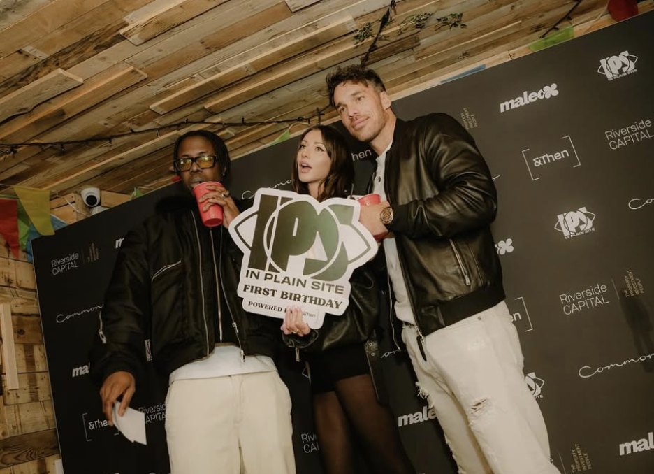 Three guests holding an In Plain Site First Birthday sign in front of a sponsor backdrop